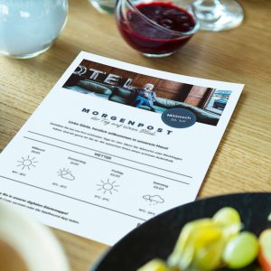 Frühstückstisch mit der ausgedruckte Hotelzeitung von Gastfreund