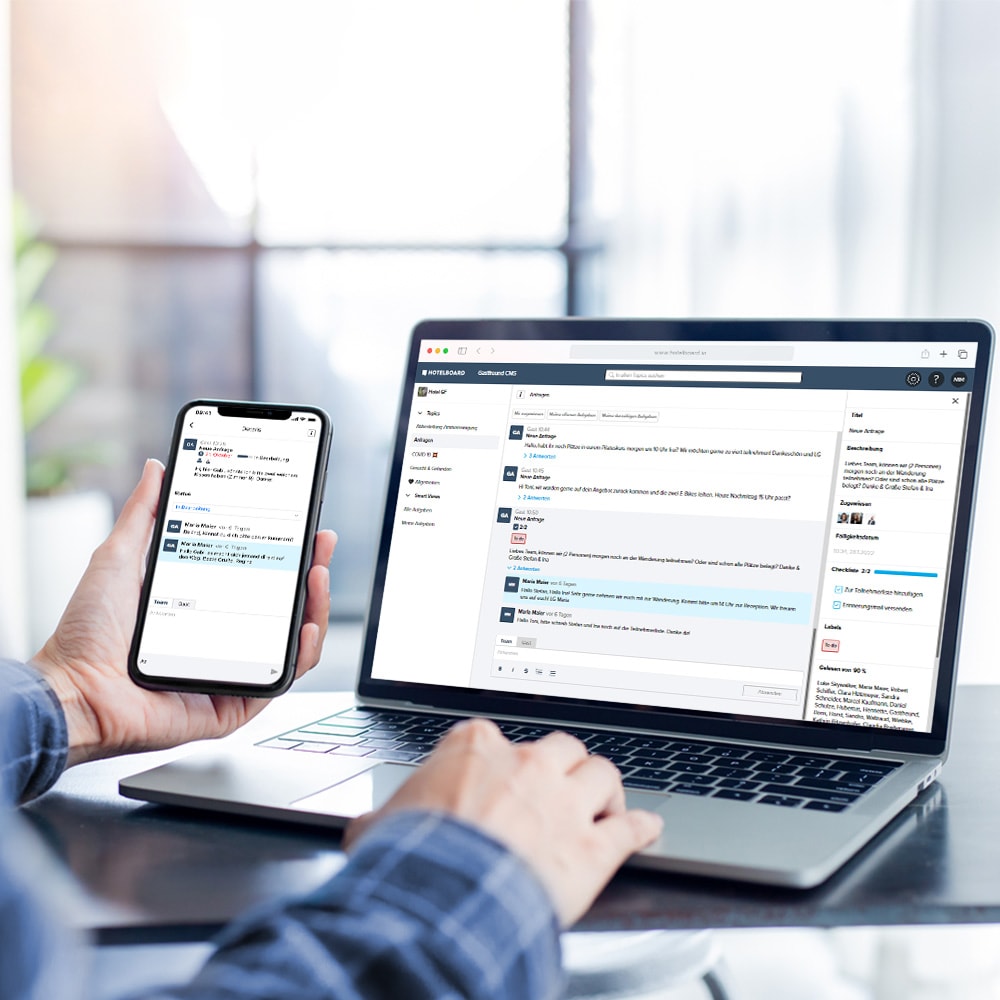 Ein Mitarbeitender der die Hotel Operations Plattform Hotelboard von Gastfreund auf einem Laptop und Smartphone benutzt