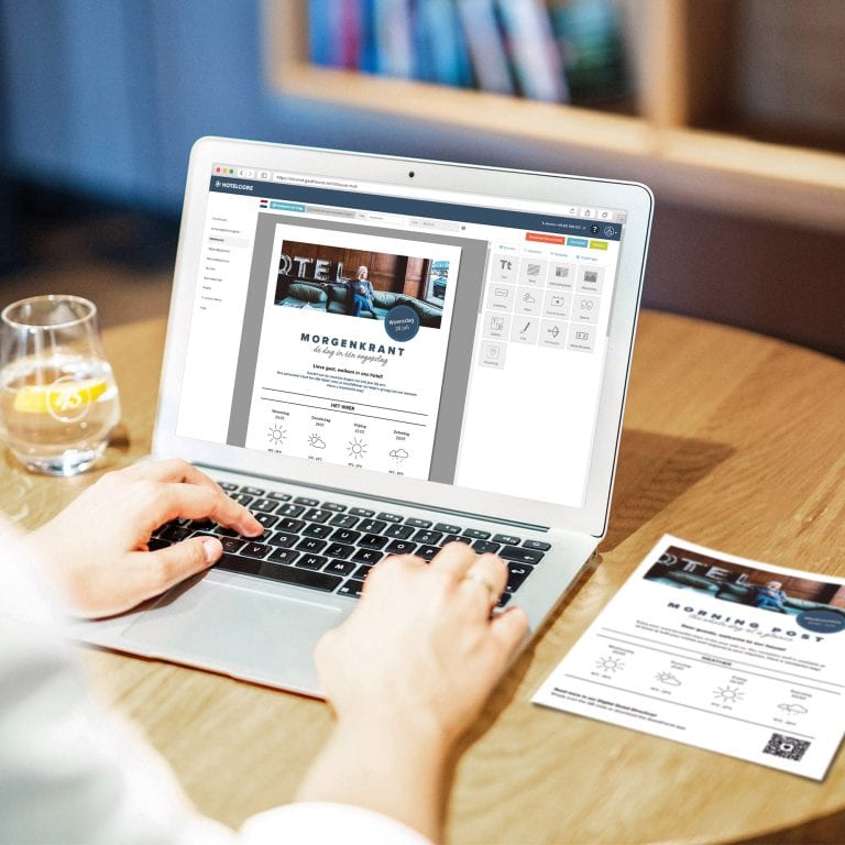 Een medewerker van het hotel stelt op de laptop met de online editor van Guestfriend per drag-and-drop de hotelkrant samen