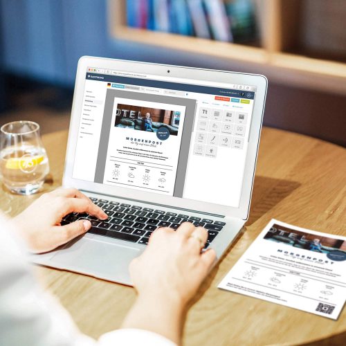 Ein Mitarbeiter des Hotels erstellt auf dem Laptop die Hotelzeitung mit dem Online-Editor mit Drag-and-Drop Funktion von Gastfreund
